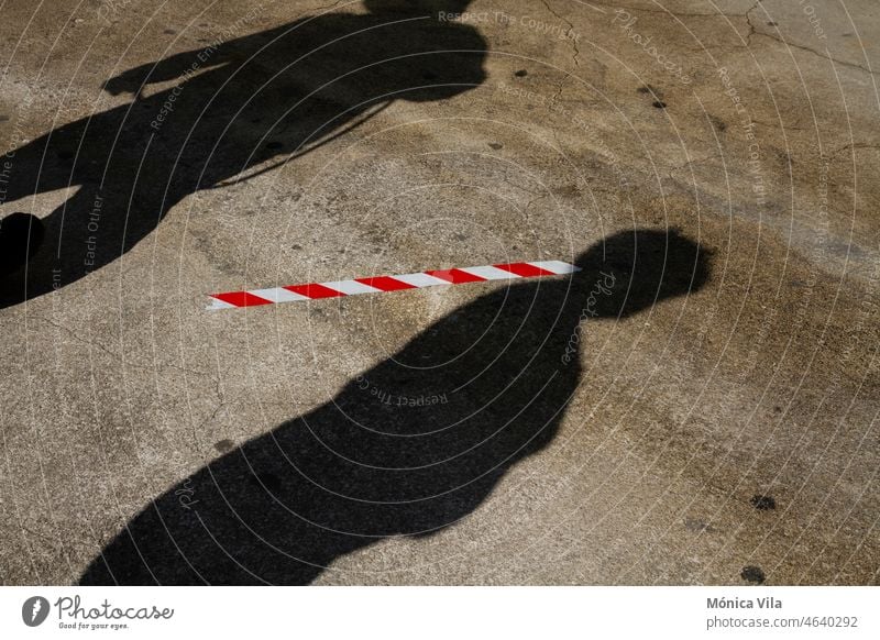 The shadow of two people on the street is separated by social distance markings on the asphalt to maintain a safe distance due to covid shadows sars covid 19