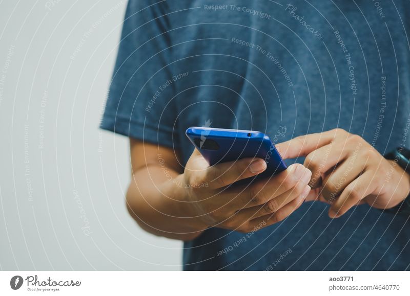 man in a blue shirt is pressing a mobile phone on background. copy space smartphone close up cellphone smart phone using device striped electronic holding