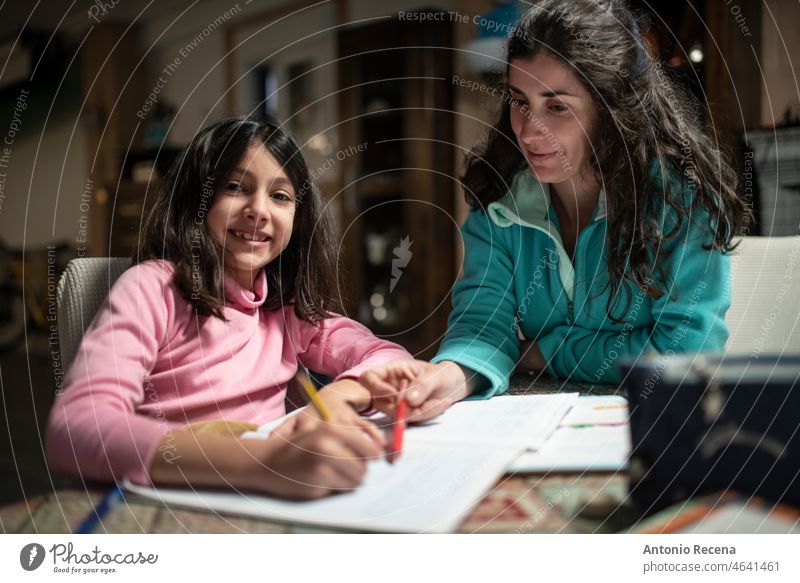 Mother helps daughter to do homework, real people in tracksuits in the garage at home children chores domestic realistic books student activity caucasian