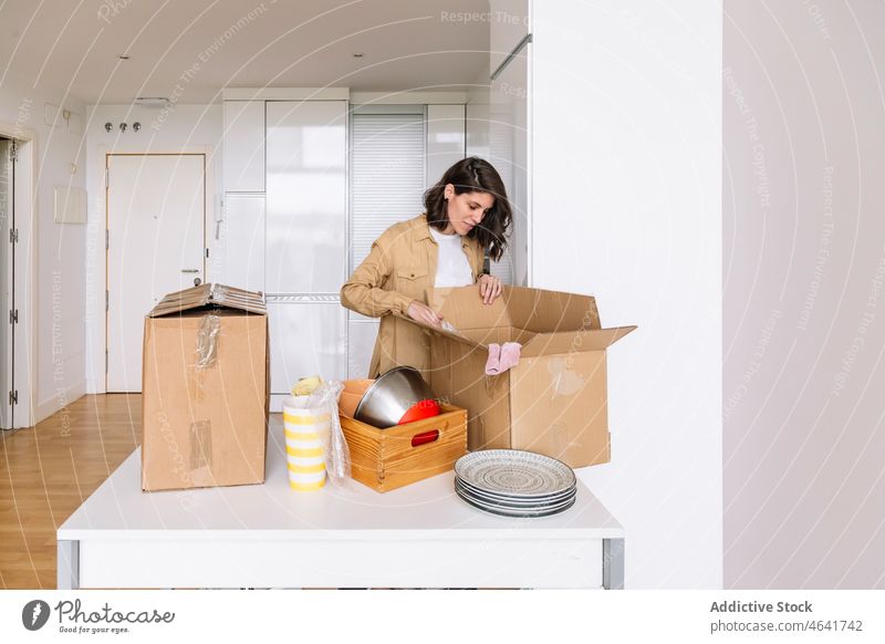 Woman unpacking carton box on floor woman move in apartment kitchen belonging table open female package new dwell residential homeowner mortgage property