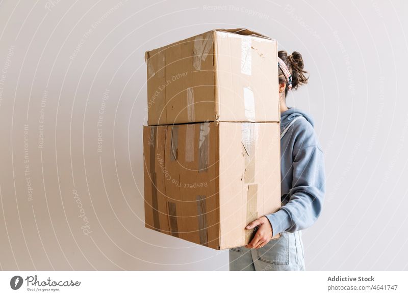 Positive woman carrying carton boxes relocate belonging stack mortgage homeowner female casual optimist young cardboard package move in pile dwell residential