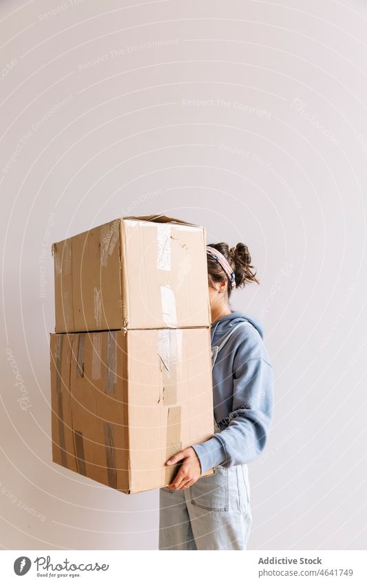Positive woman carrying carton boxes relocate belonging stack mortgage homeowner female casual optimist young cardboard package move in pile dwell residential