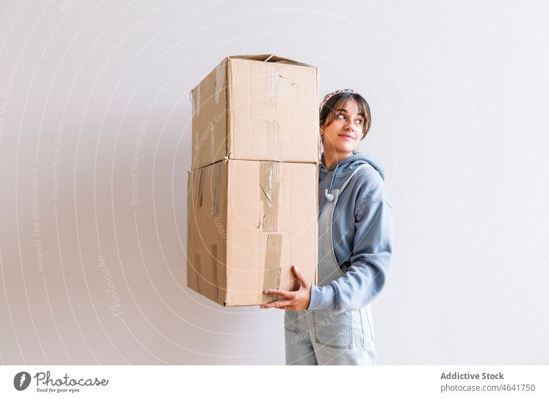 Positive woman carrying carton boxes relocate belonging smile stack mortgage homeowner positive female casual optimist young cardboard package move in happy