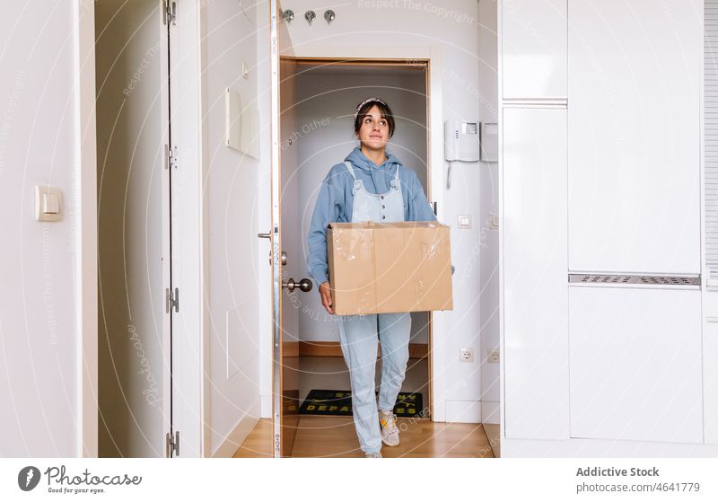 Young female moving in new apartment woman carry box move in entrance together belonging relocate home casual flat mortgage property cardboard carton rent