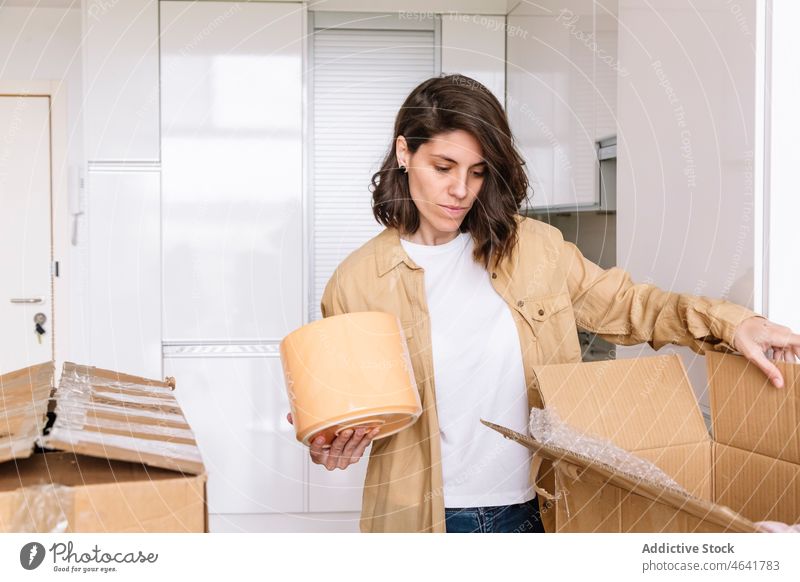 Woman unpacking carton box on floor woman move in apartment kitchen belonging table open female package new dwell pot residential homeowner mortgage property