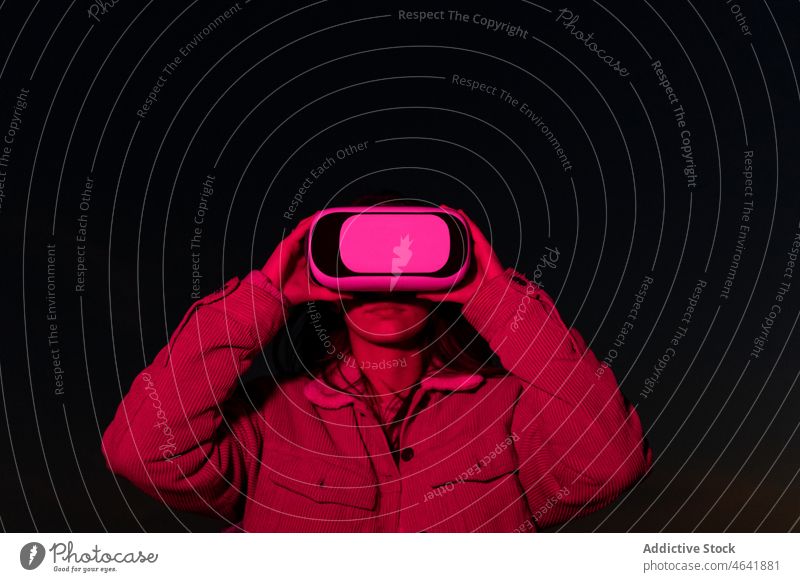 Woman watching virtual reality in glasses at night woman vr goggles using explore neon dark digital female immerse futuristic light gadget innovation lady
