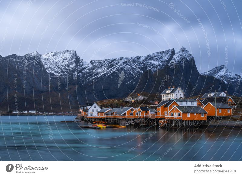 Small coastal village with cottages in bay near snowy mountains settlement sea house shore residential landscape lofoten island reine norway tranquil fjord