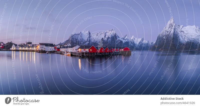 Picturesque view of calm river near cottages and snowy mountains village winter shore ridge house range settlement sky reine norway lofoten town scenic water