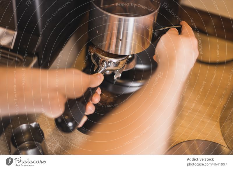 Barista inserting portafilter in stainless coffee grinder barista ground fresh machine appliance coffee shop prepare professional work maker metal cafe