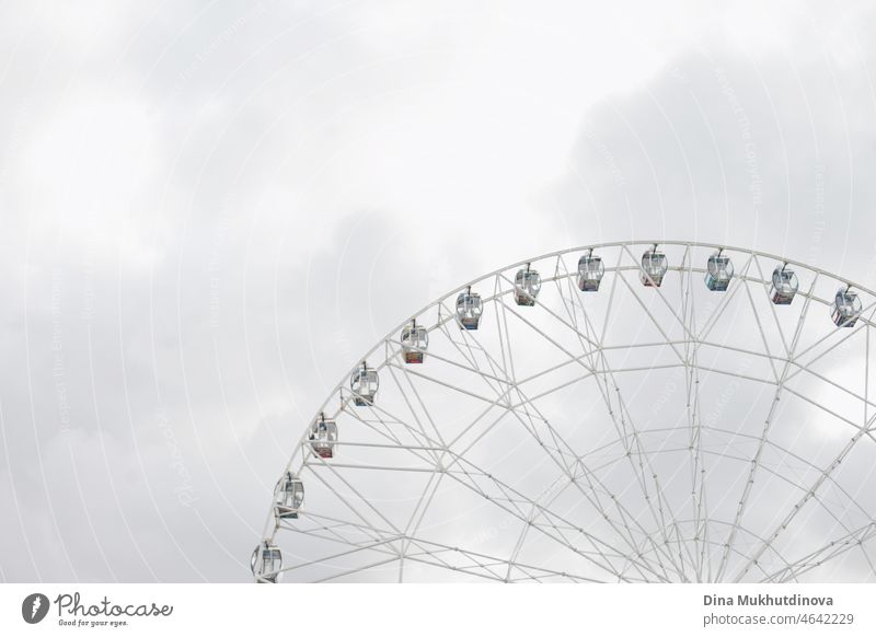 A part of ferris and cloudy gray sky. Desaturated background with ferris. Light, grey, white, sky, ferris wheel. amusement amusement park horizontal weather