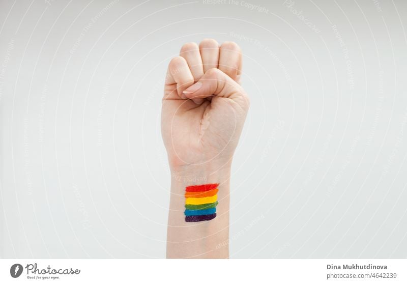Hand raised in support for lgbtq+ community with rainbow flag painted on the wrist - activism. Allies and allyship. Queer lgbt pride. Symbol, emblem, sign on human hand. peaceful, isolated, spectrum, freedom.