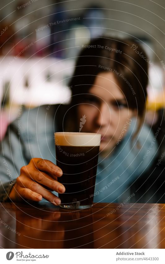 Barman checking glass with dry stout woman bartender beer beverage alcohol serve booze work counter concentrate pub female drink cafe focus lady service prepare