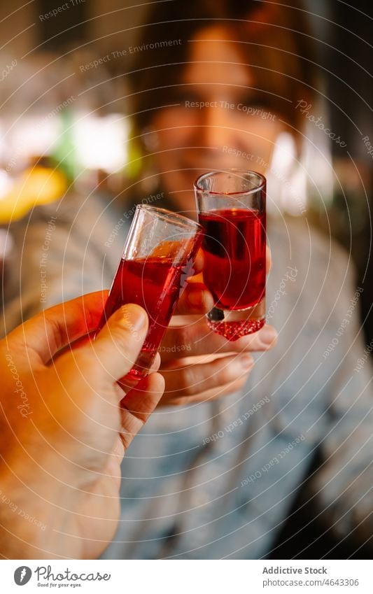Anonymous bartender clinking glasses with blood shots with faceless person woman beverage alcohol toast cheers booze work concentrate pub female drink cafe lady