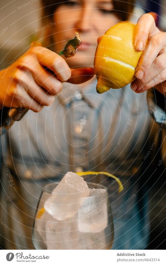 Bartender adding lemon zest into glass woman bartender citrus work fruit ice cube cold worker service workday staff workplace female lady calm pub attractive