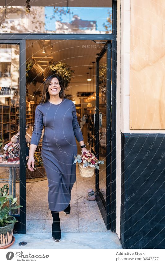 Pregnant female with basket in hand leaving shop woman street smile cheerful city eco friendly pregnant positive prenatal long hair pregnancy store feminine