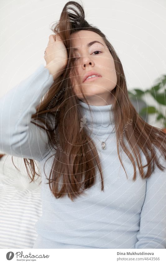 portrait of a brunette woman with long hair at home in casual clothes, fixing her hair person young confidence lady happiness caucasian female leadership model
