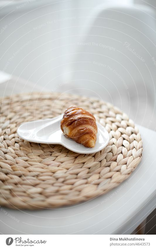 Freshly baked french croissant on a beige place mat on white table at home in the morning, at hotel room or cafe no people breakfast freshness healthy lifestyle