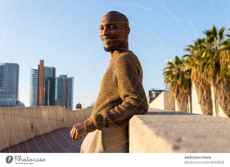 Content black man on street border pastime urban style city building street style appearance male bald african american unshaven guy self assured smile beard