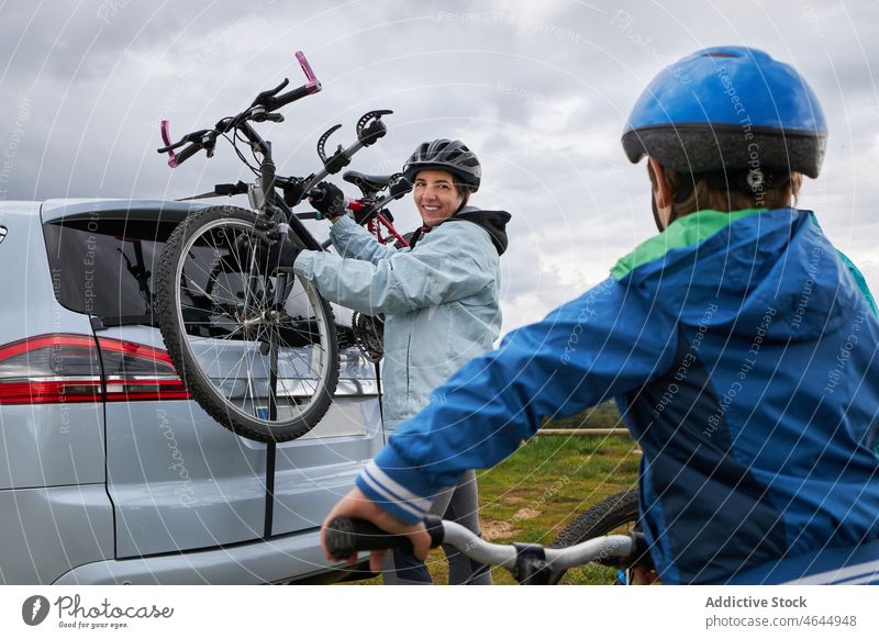 Woman with son taking bicycle from car trunk mother bike countryside rack hobby activity pastime journey road trip nature woman boy kid motherhood grassy