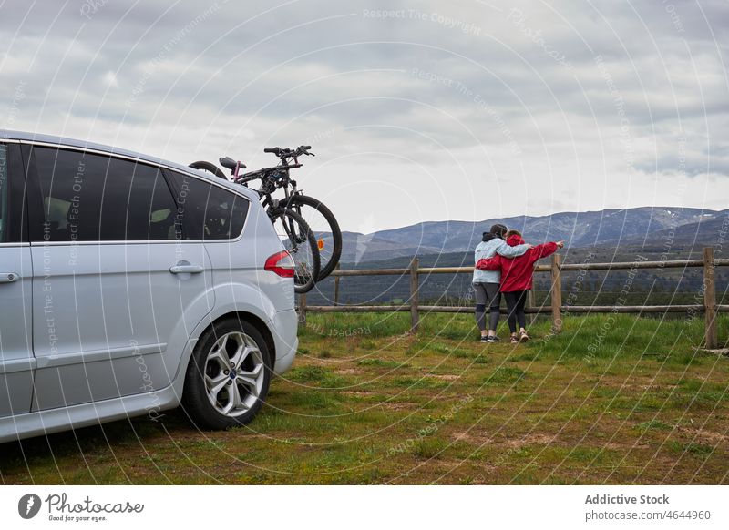Anonymous mother with kid admiring mountains near car with bicycle countryside son hobby embrace activity pastime admire enjoy journey road trip nature woman