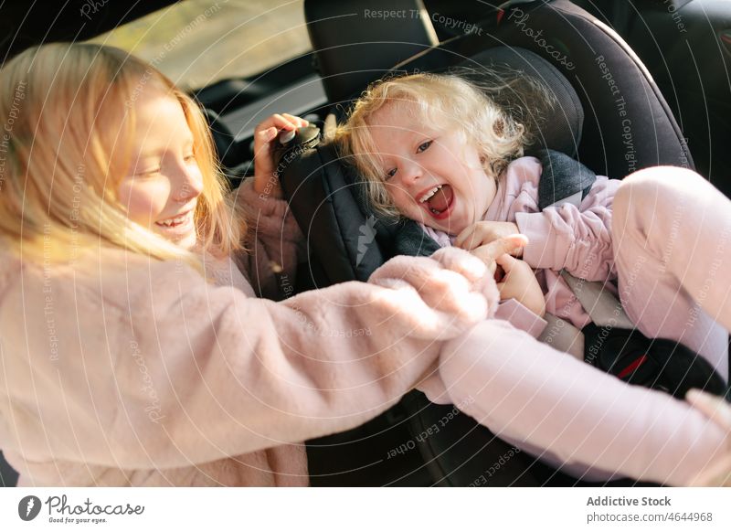 Sisters playing in modern car sister girl playful having fun road trip ride pastime passenger automobile commute seat vehicle journey safety children transport