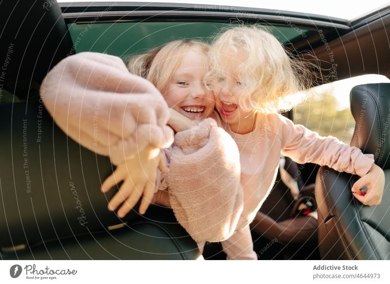 Positive sisters playing in car girl playful having fun road trip pastime passenger automobile commute vehicle journey children transport leisure adventure