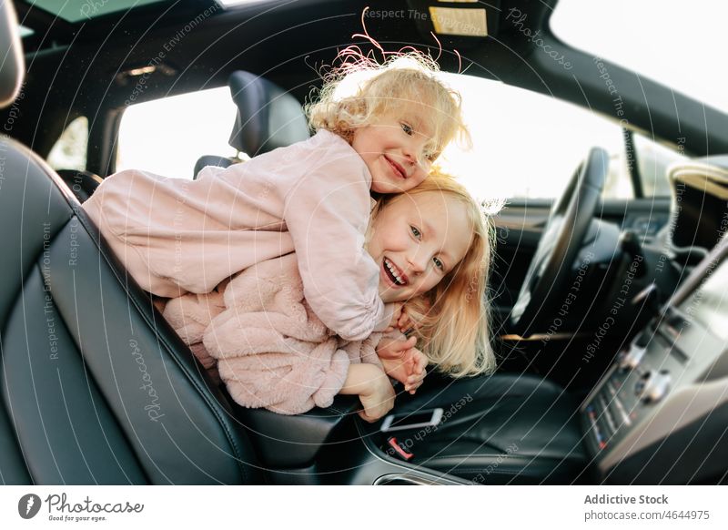 Positive sisters playing in car girl playful having fun road trip pastime passenger automobile commute vehicle journey children transport leisure adventure