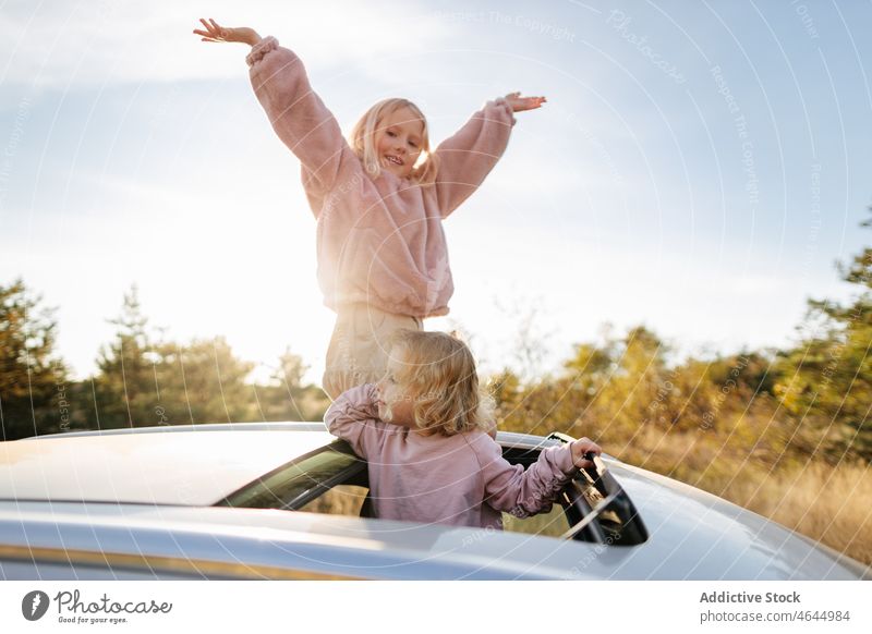 Sisters standing in sunroof of car sister girl road trip pastime passenger countryside nature automobile commute vehicle journey children transport leisure