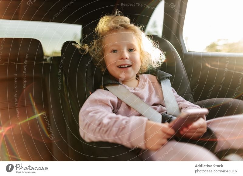 Cute girl playing on smartphone in car game child automobile passenger ride road trip rest commute seat vehicle journey transport leisure cellphone entertain