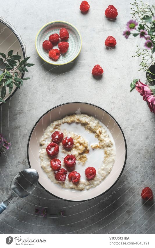 Homemade vegan porridge bowl with raspberries homemade grey concrete kitchen table spoon healthy breakfast idea summer fruits top view background berry