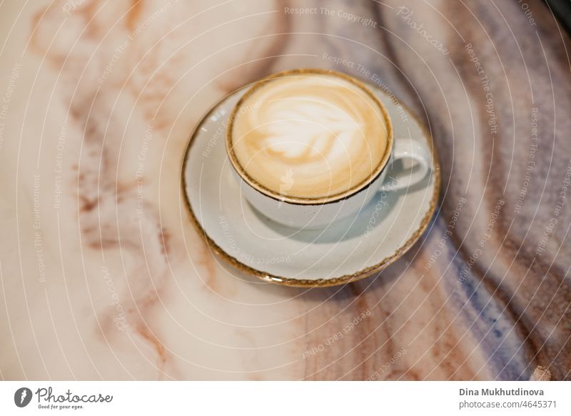 A cup of cappuccino coffee on a marble textured table at home or cafe in cozy warm lighting caffeine desk liquid copy space coffee cup break relaxation