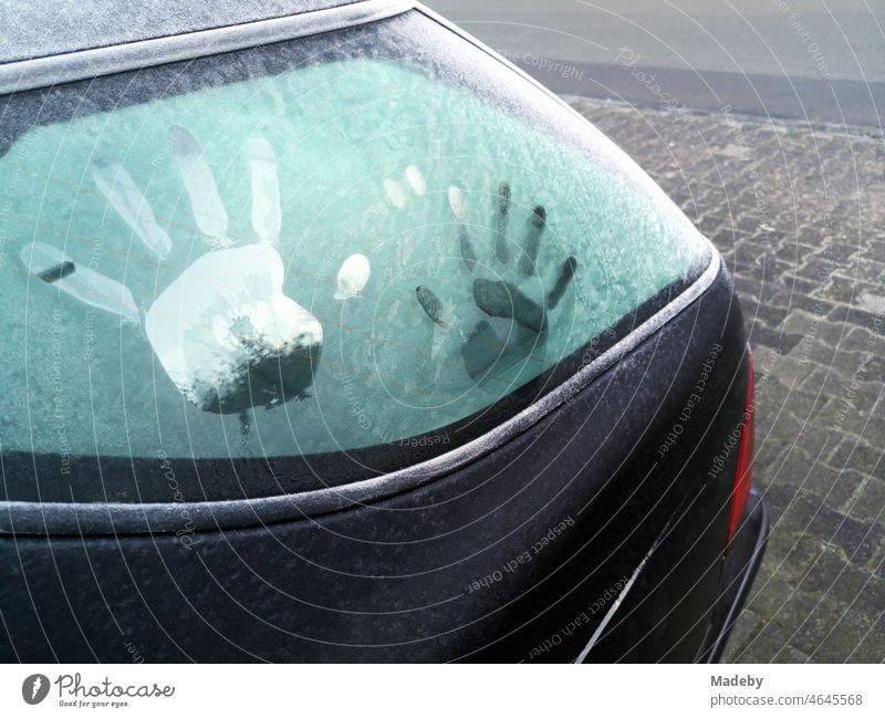 Imprint of children's hands on the rear window of an old car iced over by hoar frost in winter in Oerlinghausen near Bielefeld on the Hermannsweg in the Teutoburg Forest in East Westphalia-Lippe