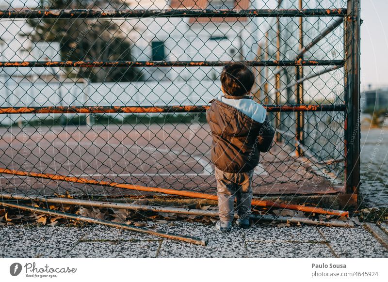 rear view child looking through chainlink fence Rear view Child childhood 1 - 3 years Colour photo Lifestyle Chain link Fence Infancy Exterior shot Day