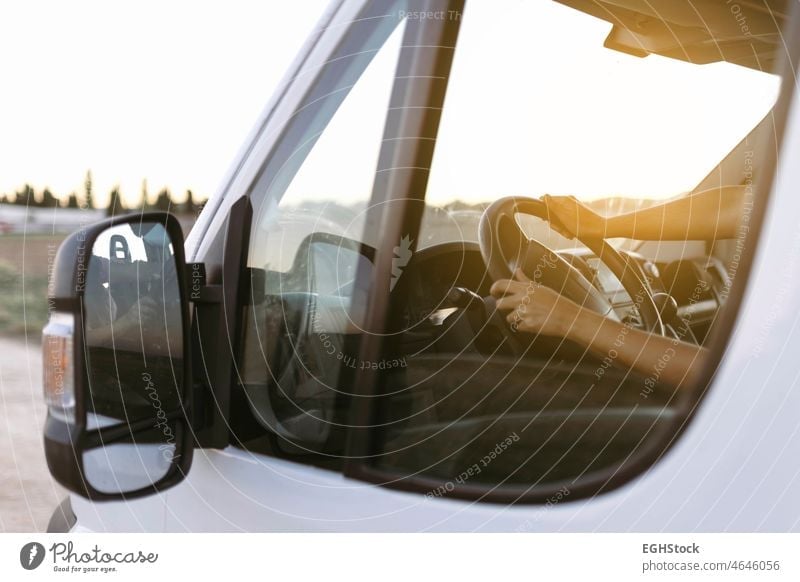 View from the outside of the steering wheel of a van and woman hands at sunset before starting the trip driving adventure airbag atmosphere auto automobile