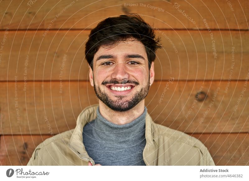 Bearded man in outerwear near wooden wall portrait individuality appearance gaze cool confident personality male glance beard jacket brunet self confident