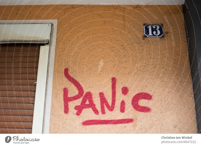 PANIC is written in red color on the orange painted facade of the house with the number 13 panicky Panic Graffito house wall House number 13 Digits and numbers