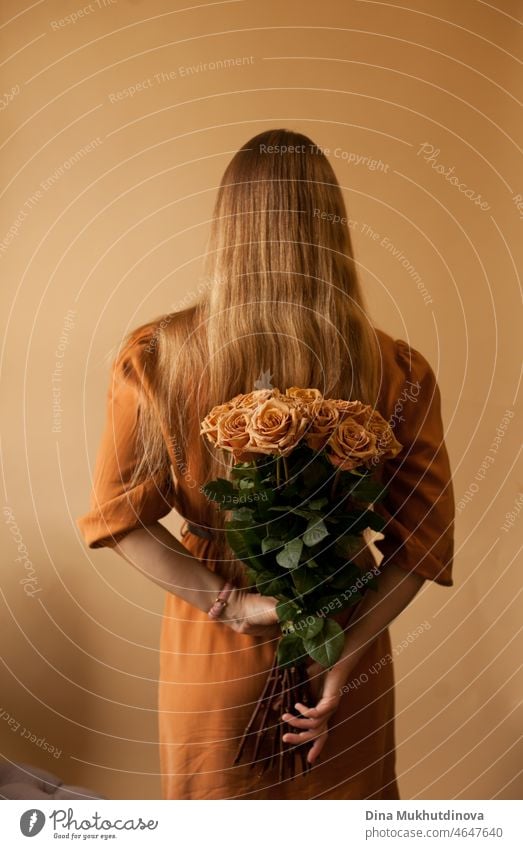 Woman in brown dress holding brown roses on beige brown background, floral concept image woman coffee Earthy beige background beige-brown Monochrome