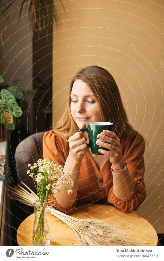Beautiful woman in brown dress at cafe drinking coffee from green cup, being calm, thinking and relaxing person pretty female portrait young relaxation