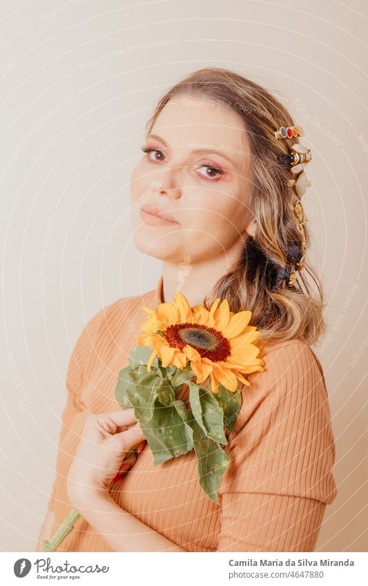 Portrait of woman holding a sunflower. Woman with clip-on hair accessories on cream background. Autumn concept. autumn beautiful beauty copy space face fashion