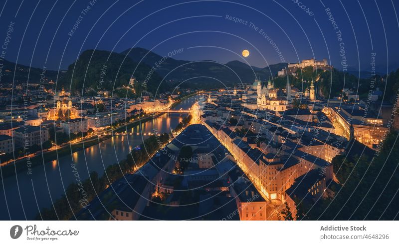 Salzsburg cityscape with illuminated buildings at night time canal mountain street waterfront house austria glow district light town residential range river