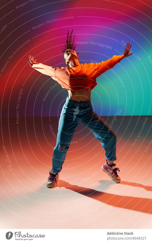 Happy woman dancing with raised hands in colorful studio dancer move skill rehearsal stretch happy projector perform smile female energy dynamic practice