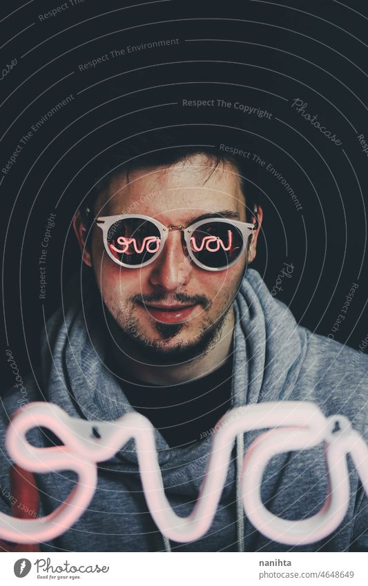 Young man holding a neon light in front of him party male reflection glasses retro futuristic future progress techno technology mystery night dark darkness