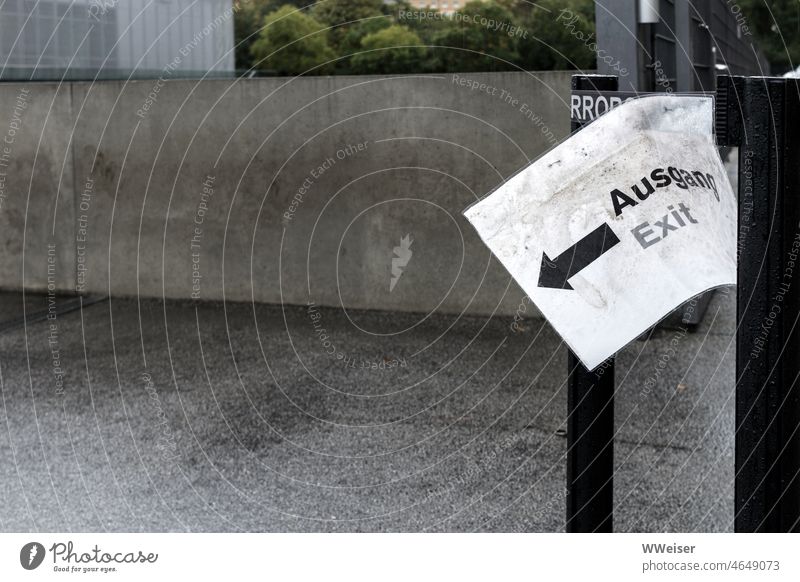 Concrete, rain, dreariness. If anyone wants to get out - the exit is over there. Way out Clue Arrow sign Piece of paper Paper Rain Wet Damp Deserted Empty