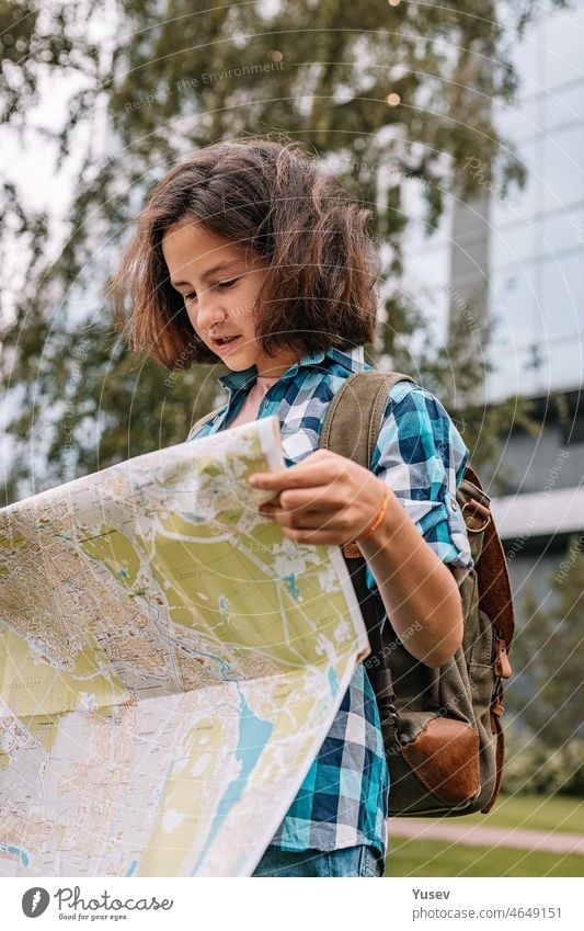 Hipster young girl looks at the map. Cute brunette teen girl travels on summer vacation. Vertical shot youthful Girl Looking Map Brunette Teenage Girls Summer