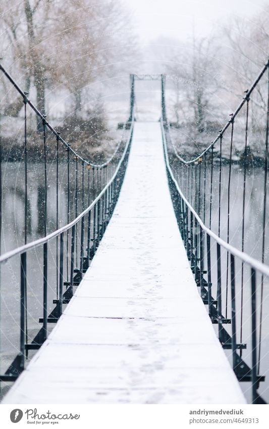 Pedestrian suspension bridge made of steel and wood across the river, winter landscape path hanging forest footbridge travel nature view wooden suspended park