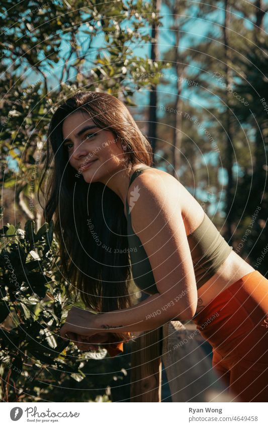 Spanish young woman leaning on a fence in a park. daydream forrest state park scenary travel elegance hispanic latina clear sky blue confident motivated