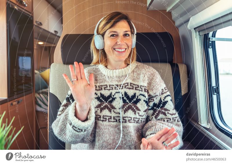 Happy woman waving on video call from her camper van happy looking camera videoconference headphones remote work travel smiling person freckles chat interview