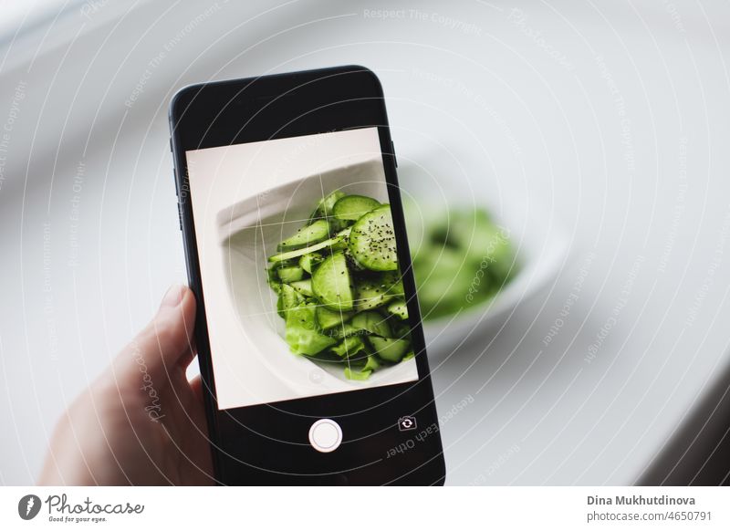 Holding mobile phone near plate of green salad - technology mock up for healthy eating lifestyle. Mock up of mobile phone and healthy food, counting calories and eating healthy. eating disorder treatment therapy.