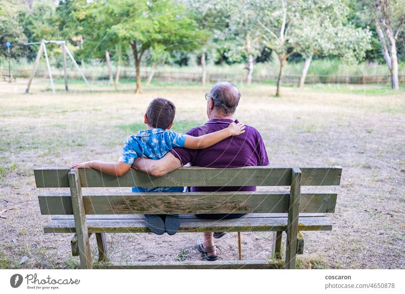 Grandfather and his grandson sitting on a bench in the park activity aging back boy child childhood elderly family friends generation grandchild grandfather