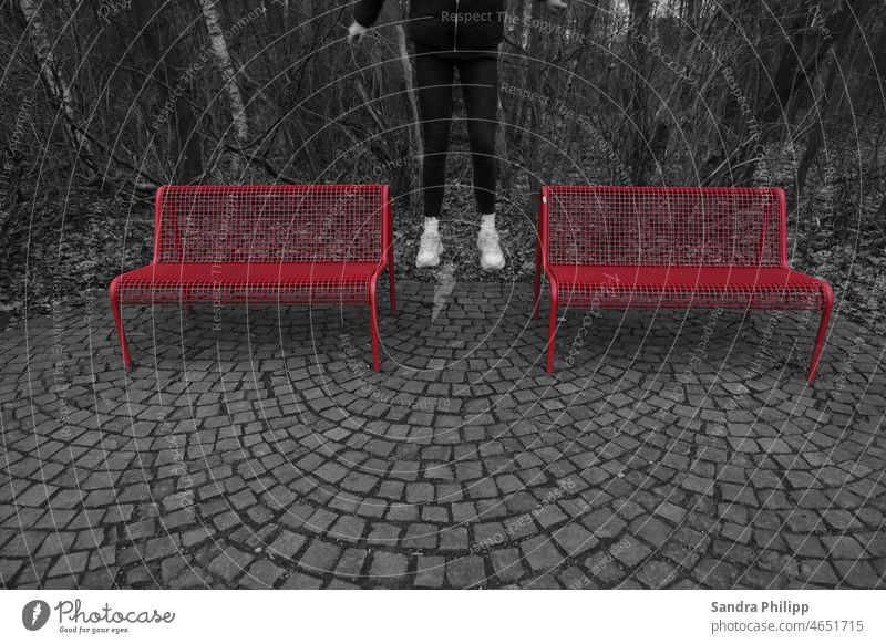 Color key effect photo, girl jumping between two red benches Legs Jump Movement Exterior shot colour contrast Black Red trees monocrom Feet Human being pavement